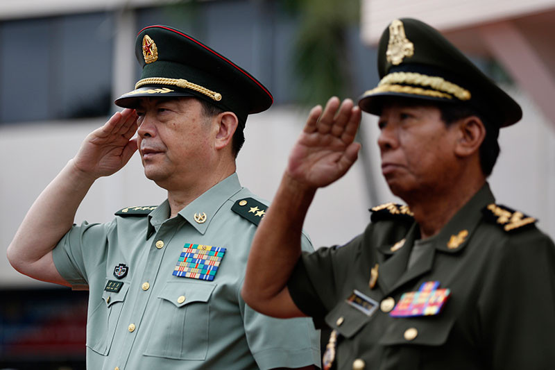 Chinese Defense Minister Chang Wanquan, left, and Cambodian Defense Minister Tea Banh salute during a ceremony in Phnom Penh on Friday. (Siv Channa)