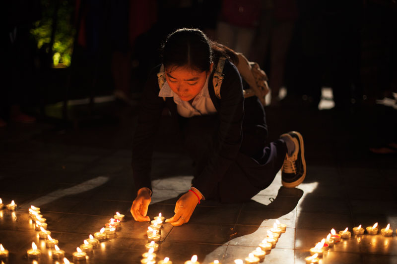 A woman lights a candle at a memorial for victims of the Paris attacks, at the Institut Francais in Phnom Penh on Tuesday. (Jens Welding Ollgaard/The Cambodia Daily)