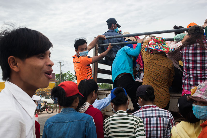 Workers at the Manhattan special economic zone in Svay Rieng province's Bavet City climb onto trucks after being sent home Tuesday. (Jens Welding Ollgaard/The Cambodia Daily)