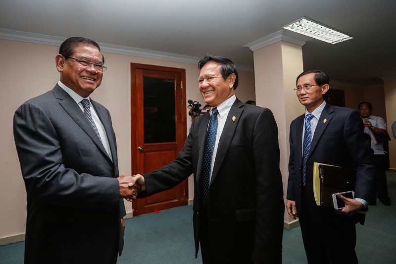 Interior Minister Sar Kheng, left, shakes hands with deputy opposition leader Kem Sokha before a meeting yesterday at the National Assembly. (Siv Channa/The Cambodia Daily)
