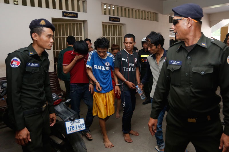 Two men suspected in a deadly armed motorcycle robbery in Phnom Penh's Tuol Kok district, center left and center right, are led into the Phnom Penh Municipal Court on Monday. (Siv Channa/The Cambodia Daily)