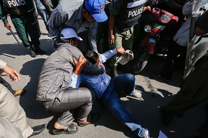 Former Capitol Tours bus drivers help up a fellow driver who was knocked down during a scuffle with police in Phnom Penh on Friday. (Siv Channa/The Cambodia Daily)