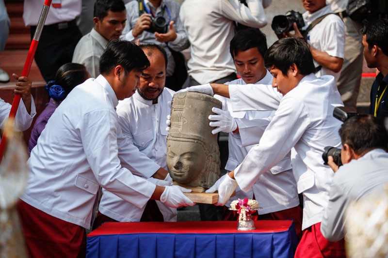 Restoration staff prepare to place the head of the Harihara statue atop its body at the National Museum in Phnom Penh on Thursday. (Siv Channa/The Cambodia Daily )