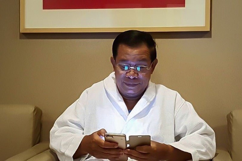 Prime Minister Hun Sen uses a smartphone in a photograph posted to his Facebook page in February.