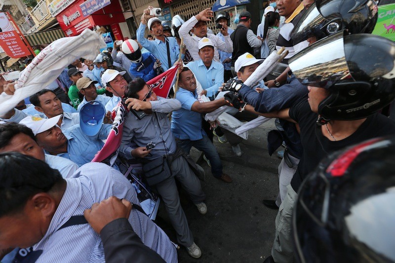 Helmeted tuk-tuk drivers beat back a group of sacked bus drivers protesting outside the Capitol Tours bus company’s headquarters in Phnom Penh on Saturday. (Satoshi Takahashi)