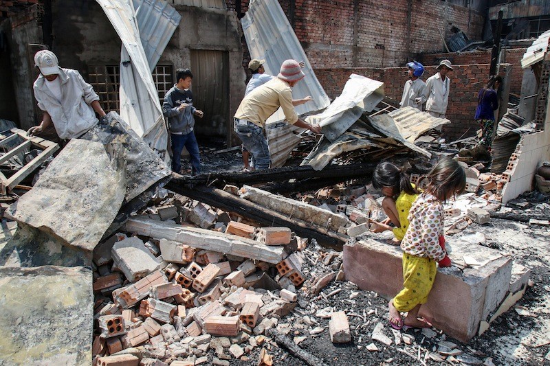 Residents sift through the remains of their homes after a fire destroyed 97 houses in Phnom Penh's Meanchey district on Monday morning. (Khem Sovannara)