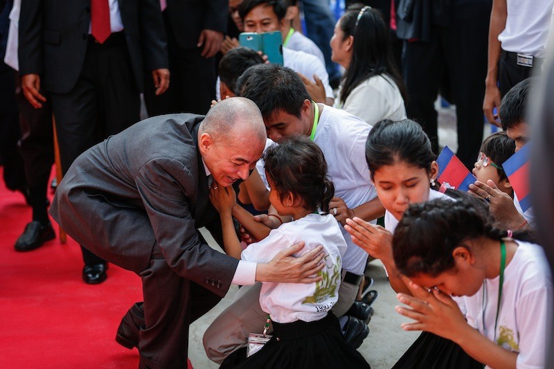 King Norodom Sihamoni embraces a student at Krousar Thmey's Phnom Penh Thmey school during the organization's 25th anniversary celebration on Wednesday. (Siv Channa/The Cambodia Daily)