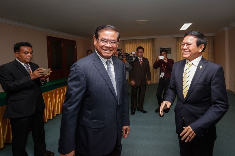 Interior Minister Sar Kheng, center, and deputy opposition leader Kem Sokha, right, greet each other at the National Assembly in Phnom Penh on Friday. (Siv Channa/The Cambodia Daily)