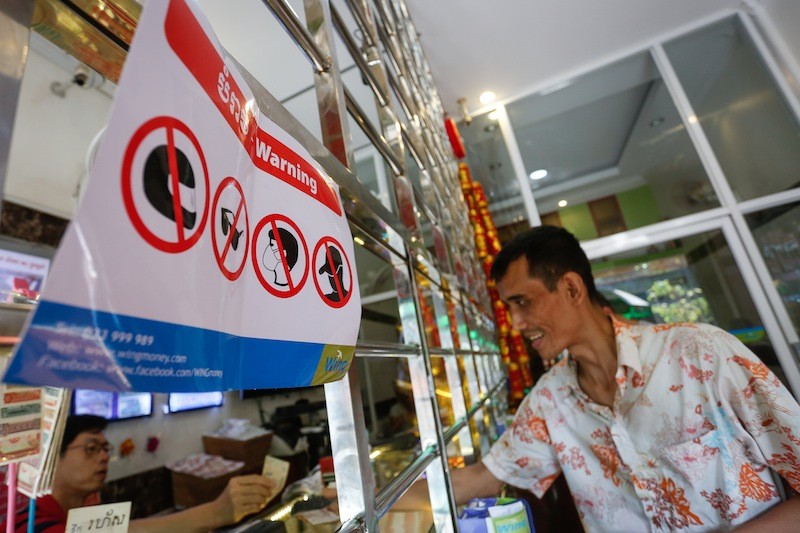A poster instructing customers not to obscure their faces—distributed by money transfer service Wing—is displayed at a money exchange in Phnom Penh on Tuesday. (Siv Channa/The Cambodia Daily)