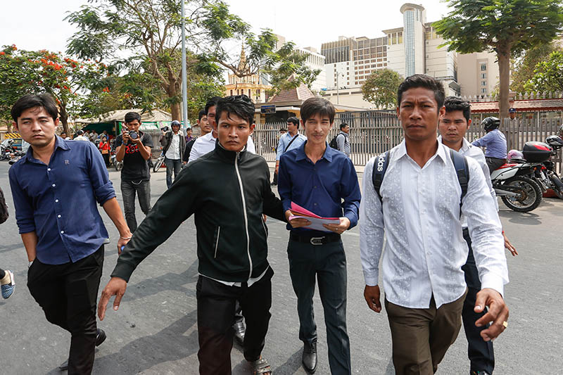 Srey Chamroeun, second from right, is escorted away from the National Assembly in Phnom Penh on Friday after submitting a petition accusing deputy opposition leader Kem Sokha of murder. (Siv Channa/The Cambodia Daily)