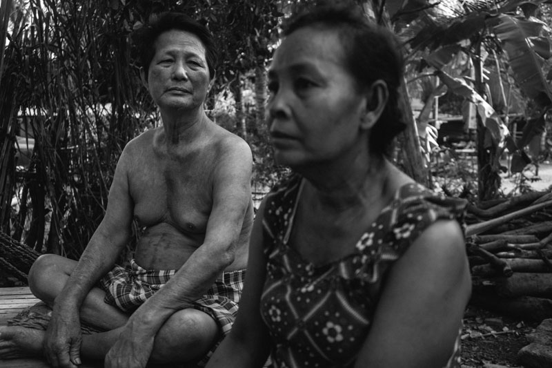 Yorn Thoeun and her husband, Troeung Long, speak outside their home in Village 77. (Hannah Reyes)