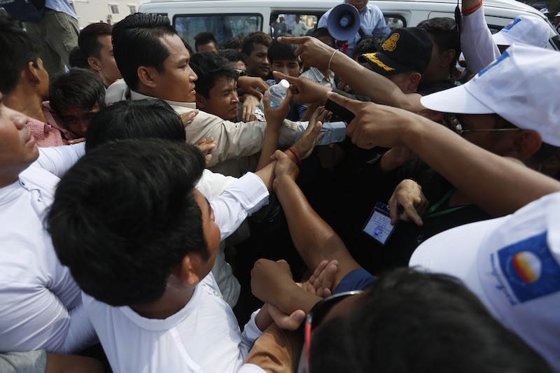 Members of a student group, left, that has been calling on deputy opposition leader Kem Sokha to publicly respond to leaked phone calls, purported to be him speaking with mistresses, face off with CNRP supporters and security guards outside a party convention in Phnom Penh on Saturday. (Siv Channa/The Cambodia Daily)
