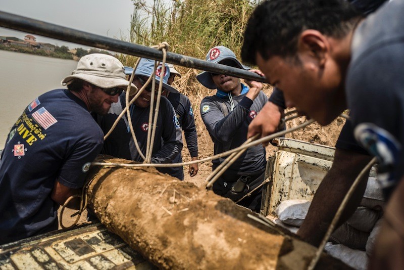 Divers from the Cambodian Mine Action Center secure a 500-pound MK-82 bomb after removing it from the Tonle Sap River in Phnom Penh on Wednesday morning. (Charles Fox) 