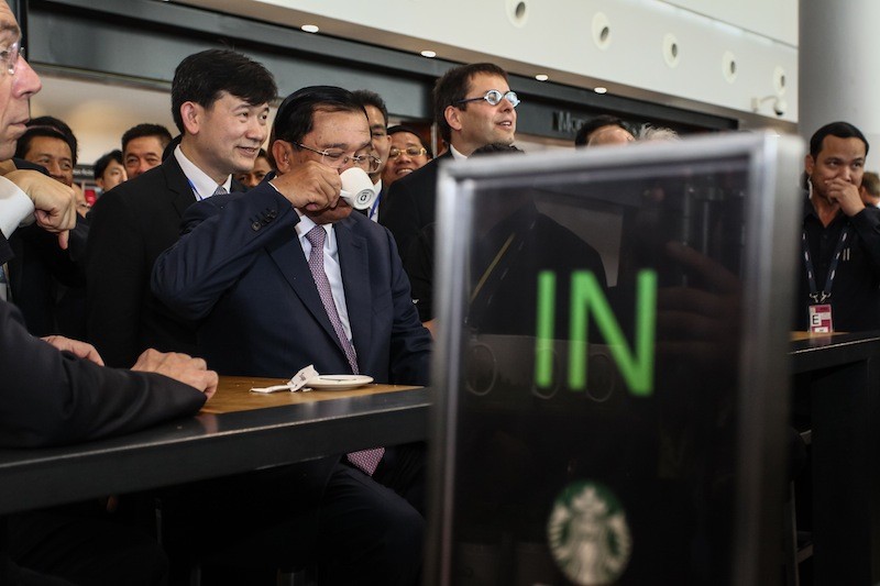 Prime Minister Hun Sen sips a beverage on Wednesday at a Starbucks outlet at Phnom Penh International Airport, where he presided over the inauguration of a new terminal. (Masayori Ishikawa)