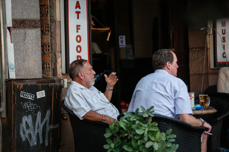 Men smoke outside a restaurant on Sisowath Quay in Phnom Penh on Friday. (Siv Channa/The Cambodia Daily)