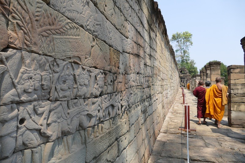 Monks walk past a segment of recently restored walls at Banteay Chhmar temple. (Olivier Cunin)