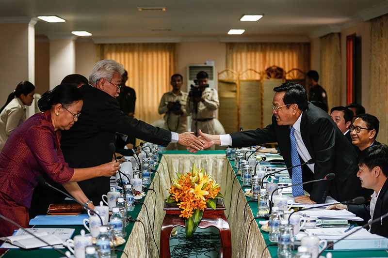 Labor Minister Ith Sam Heng, right, shakes hands with CPP lawmaker Pen Panha at the National Assembly in Phnom Penh on Thursday. (Siv Channa/The Cambodia Daily)