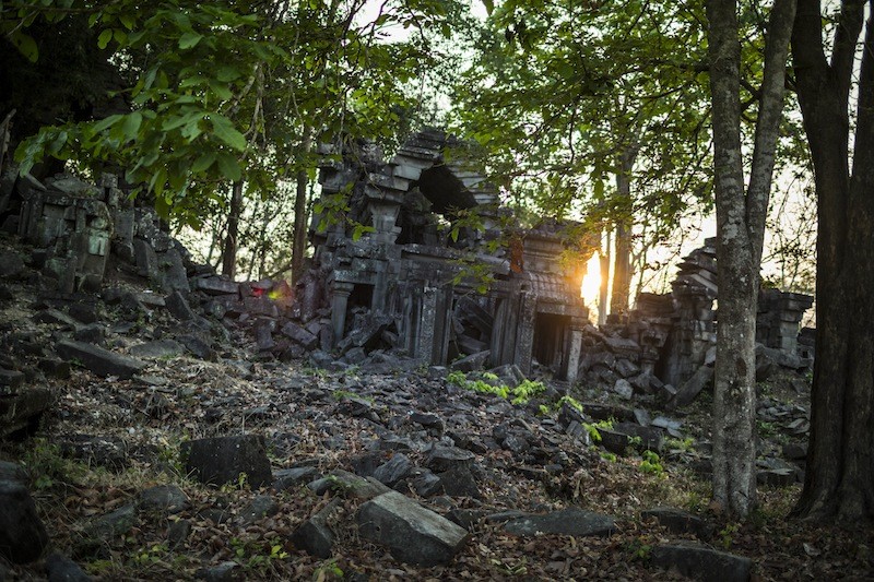 Sunlight peeks through the trees behind temple ruins at the Preah Khan of Kompong Svay complex earlier this year. (Enric Catala)