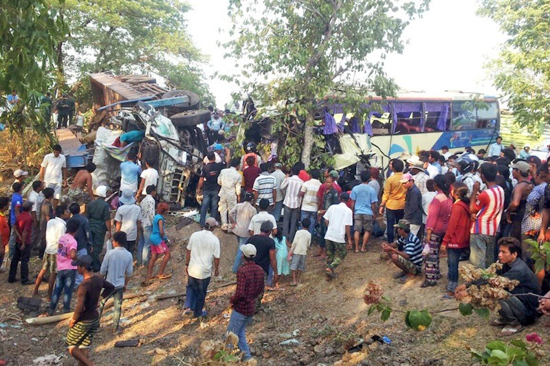 People gather around a mangled tour bus and tow truck following a deadly crash on National Road 5 in Battambang's Sangke district on Saturday afternoon. (Pang Hieng)