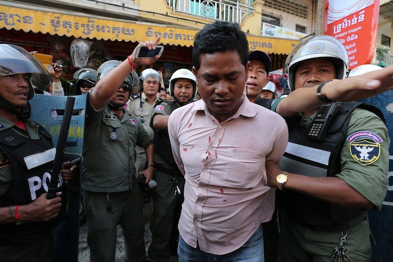 A protester is detained by police after being attacked by tuk-tuk drivers outside the Capitol Tours head office in Phnom Penh in February. (Satoshi Takahashi)