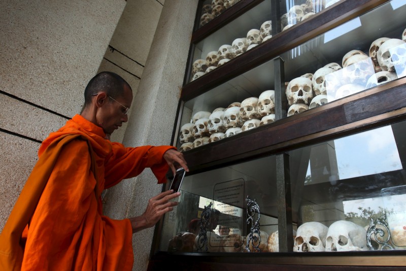 A monk uses a smartphone to take a photograph of a case containing skulls of Khmer Rouge victims at the Choeung Ek Genocidal Center in Phnom Penh on Sunday. (Pring Samrang/Reuters)