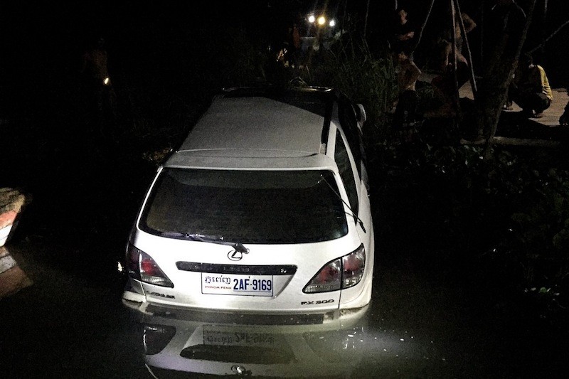 A Lexus SUV in which seven passengers drowned after its driver careened off a ferry landing in Kandal province on Sunday evening is pulled from the Bassac River later in the night, in this photograph provided by police. 