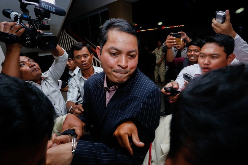 Cambodia's ambassador to South Korea, Suth Dina, is escorted from the Phnom Penh Municipal Court after being charged with unlawful exploitation and abuse of power on Thursday. (Siv Channa/The Cambodia Daily)