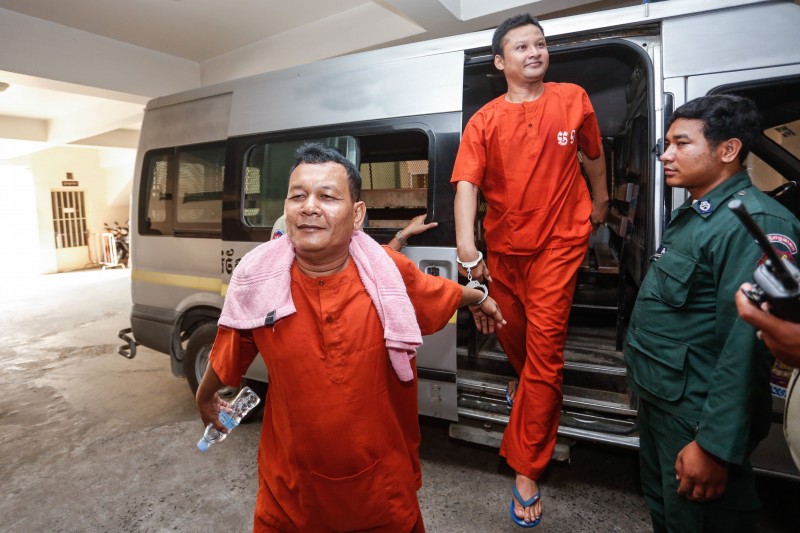 Suth Vanny, left, and Mao Hoeun, members of the Prime Minister Bodyguard Unit, smile while stepping out of a police van at the Phnom Penh Municipal Court on Thursday for their trial on charges of intentional violence for beating two opposition lawmakers in October. (Siv Channa/The Cambodia Daily)