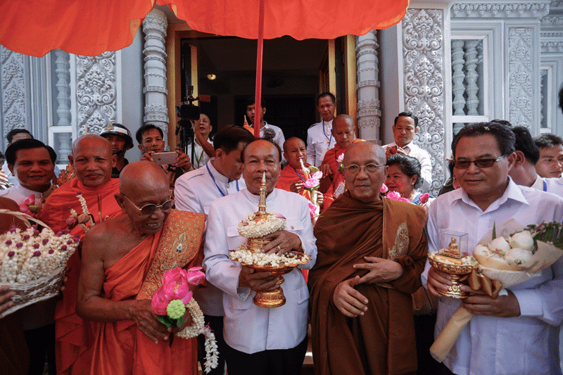 Cults and Religion Minister Him Chhem, center, carries an urn containing relics of the Buddha to the stupa on top of Odong mountain, flanked by Grand Supreme Patriarch Tep Vong, left, and Bou Kry, the supreme patriarch of the Thammayut Buddhist sect, on Friday. (Siv Channa/The Cambodia Daily}