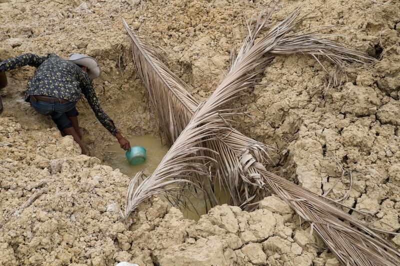 A farmer fetches water from a hole he dug in a dried-up canal in Kampot last month. (John Vink/The Cambodia Daily)