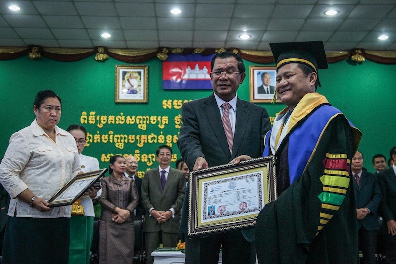 Prime Minister Hun Sen delivers an honorary doctorate to timber magnate Try Pheap during a ceremony in Phnom Penh yesterday. (Masayori Ishikawa)