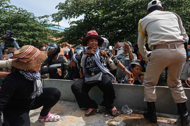 A protester from Phnom Penh’s Boeng Kak community is pushed into the bed of a police truck near Prey Sar prison on Monday morning. (Siv Channa/The Cambodia Daily)