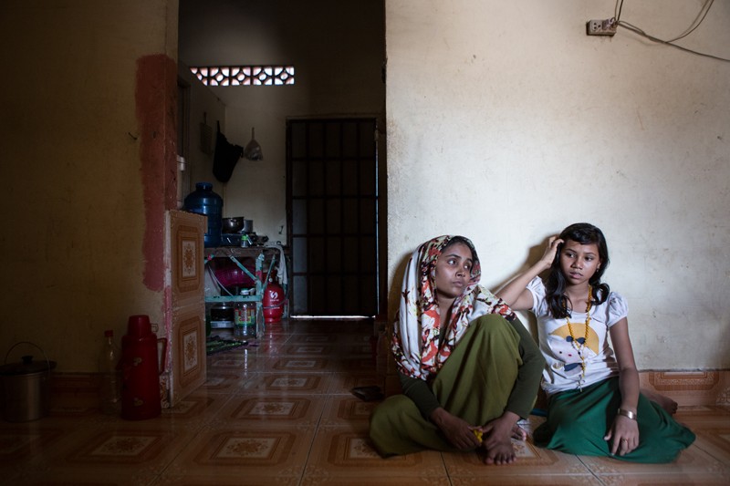 Josna, right, and her mother, Romeda Bagiom, sit on the floor of their family home in Phnom Penh’s Chbar Ampov district. (Hannah Hawkins/The Cambodia Daily)