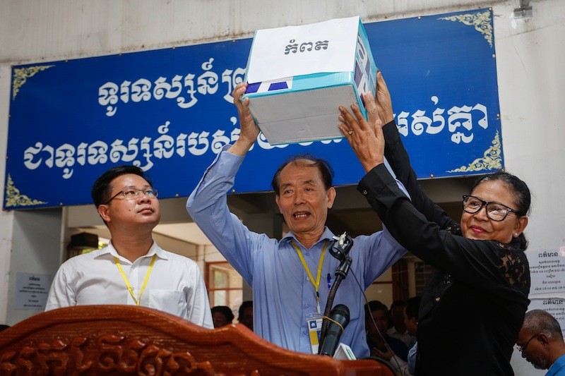 CNRP lawmaker Lim Bunsidareth, center, holds up a box of thumb-printed petitions collected by opposition activists in Kampot province, his constituency, at the party's Phnom Penh headquarters on Monday. (Siv Channa/The Cambodia Daily) 