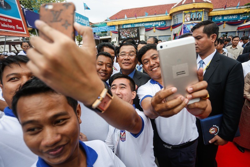 Prime Minister Hun Sen, center, poses for selfies with young supporters during a ceremony marking the CPP’s 65th anniversary at the party’s headquarters in Phnom Penh yesterday. (Siv Channa/The Cambodia Daily) 