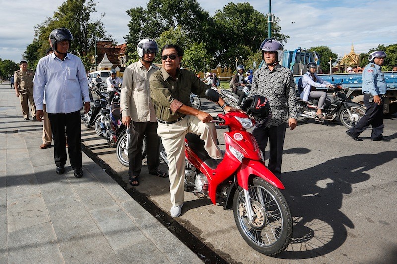     Prime Minister Hun Sen steps off a motorbike at the riverside Preah Ang Dangkeu shire in Phnom Penh on Friday. Mr. Hun Sen prayed for good luck after paying a fine for not wearing a helmet last weekend. (Siv Channa/The Cambodia Daily)