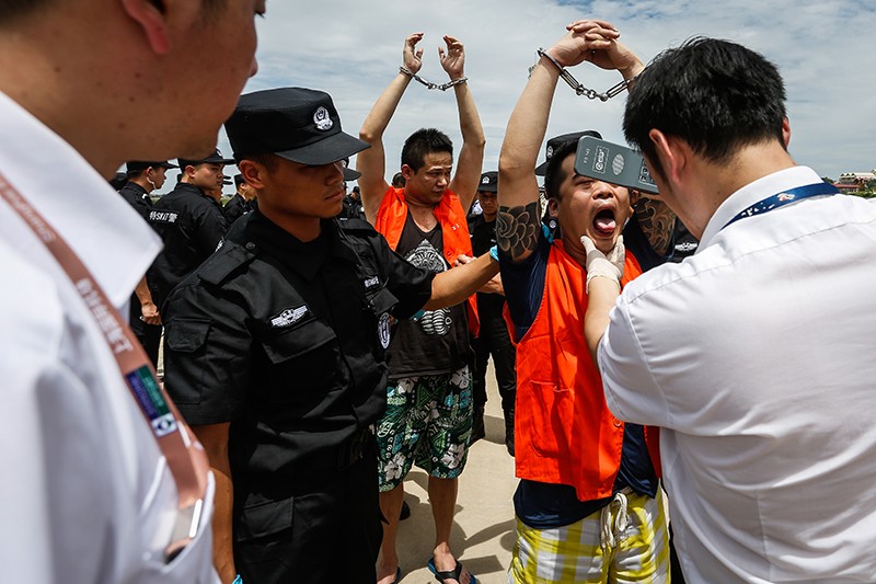 Police search Chinese and Taiwanese detainees as they prepare to board a flight to China at Phnom Penh International Airport on Friday. (Siv Channa/The Cambodia Daily)