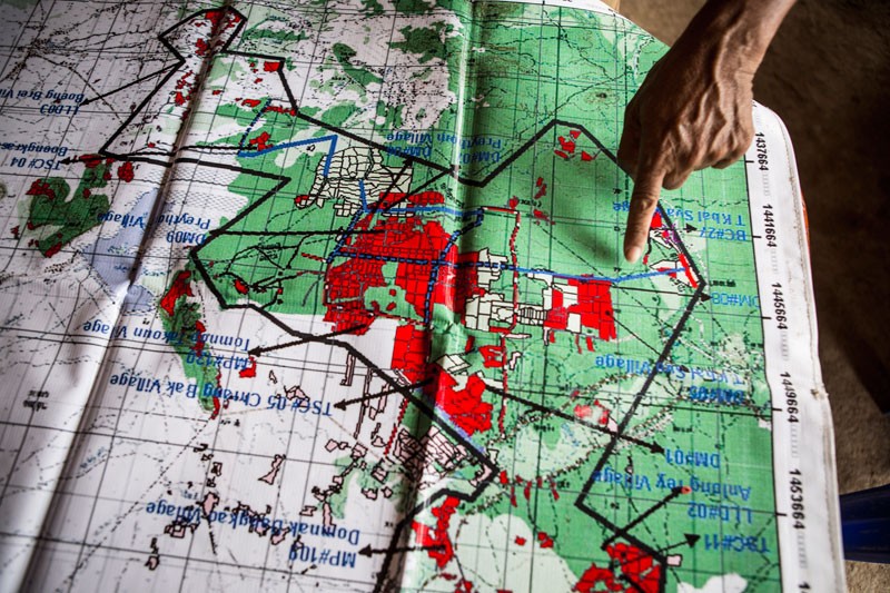 Trapeang Kbalsva village chief Dy Saroeun points at a map of the minefields around his village. (Enric Catala)