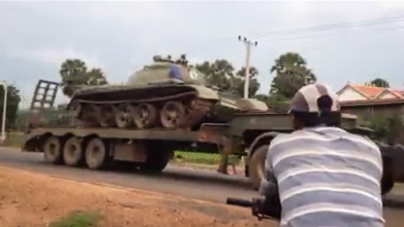 A man watches as a tank is transported along a road from Preah Vihear province to Phnom Penh on Monday, in a screenshot of a video uploaded to Facebook.