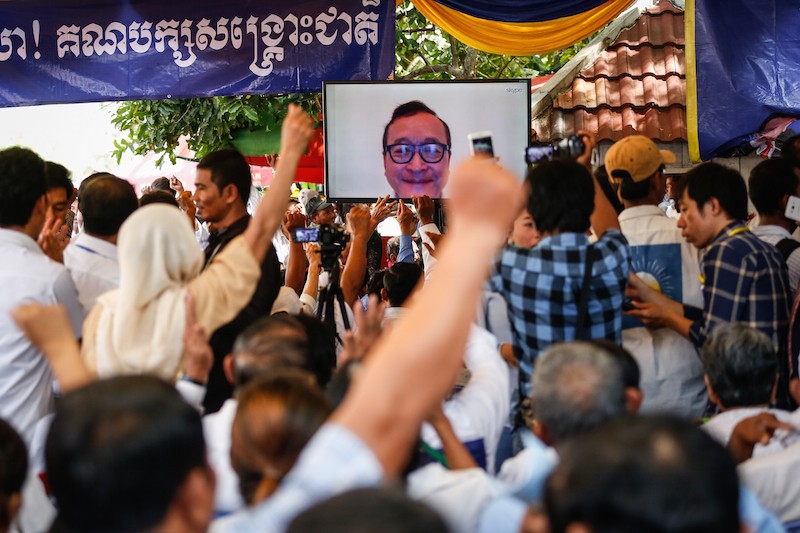  Opposition leader Sam Rainsy joins a ceremony marking the CNRP’s fourth anniversary via Skype, at the party’s Phnom Penh headquarters last month. (Siv Channa/The Cambodia Daily)