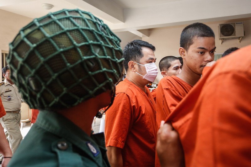 Ea Se, center, a bureau chief at the Foreign Affairs Ministry, is escorted into the Phnom Penh Municipal Court on Wednesday. (Siv Channa/ The Cambodia Daily)