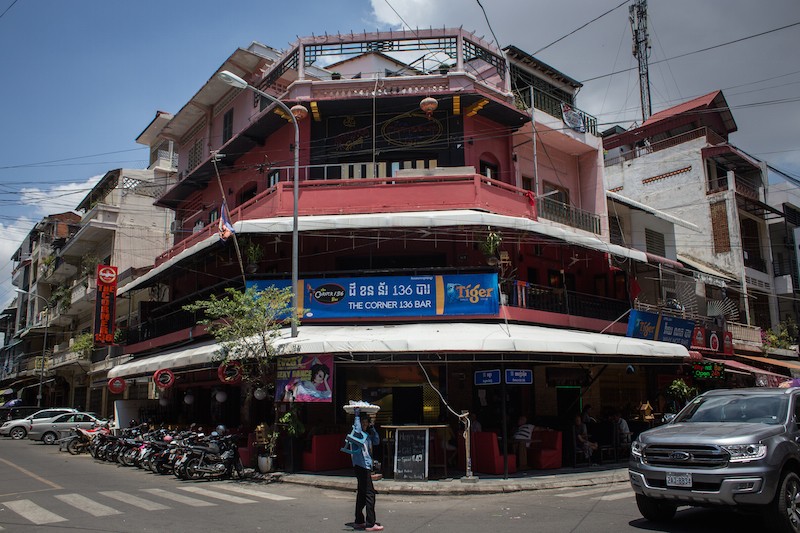 A food vendor walks past The Corner 136 Bar in Phnom Penh on Sunday. (Hannah Hawkins/The Cambodia Daily)