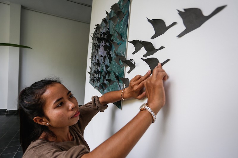 Touch Lida, a boutique saleswoman at the Plantation hotel, installs her work 'Trek' on Tuesday. (Siv Channa/The Cambodia Daily)