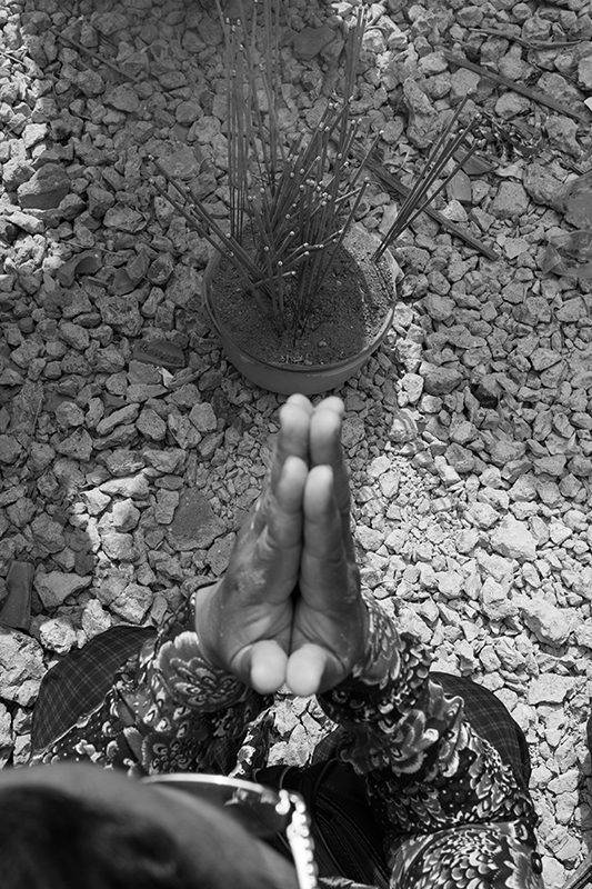 A member of the Borei Keila community, which has been embroiled in a land conflict since 2007, prays in front of a bowl containing soil from the area she was evicted from before a cursing ceremony in 2014.