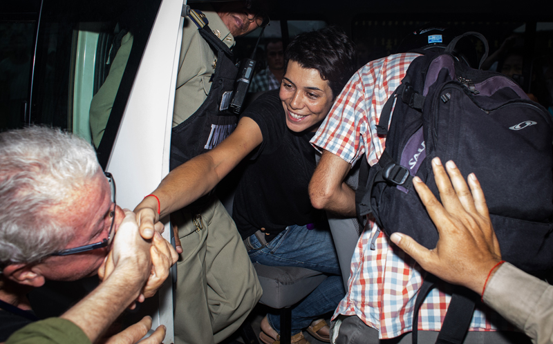 Marga Bujosa Segado shakes the hand of a friend after being pushed into a police van outside her home in Phnom Penh’s Boeng Kak neighborhood on Wednesday evening. (Hannah Hawkins/The Cambodia Daily) 