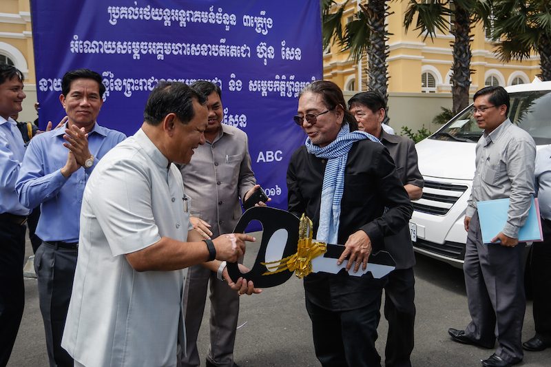Seng Bunveng, right, accepts a symbolic key to ABC radio's new vehicles from Phnom Penh governor Pa Socheatvong at City Hall on Tuesday. (Siv Channa/The Cambodia Daily)