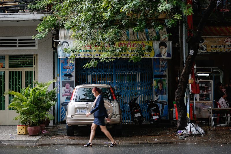 A woman walks past the Reksmey Chan Thea barbershop on Street 61 in Phnom Penh on Wednesday. (Siv Channa/The Cambodia Daily)