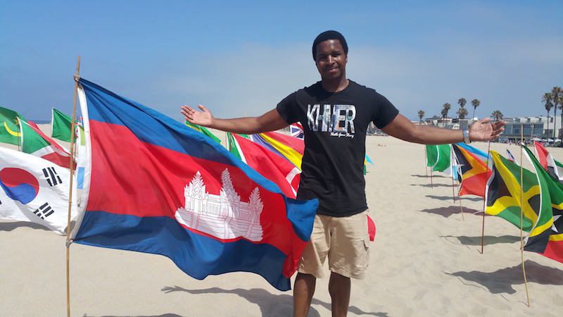 Mr. Cravens poses with the Cambodian flag on a beach