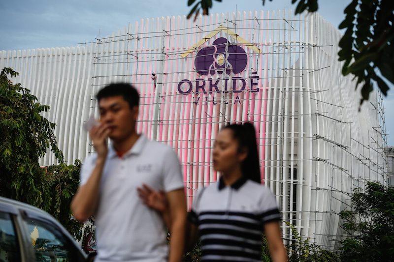 A couple walks past the Norodom Boulevard showroom for Phnom Penh's Orkide Villa development yesterday. (Siv Channa/The Cambodia Daily) 