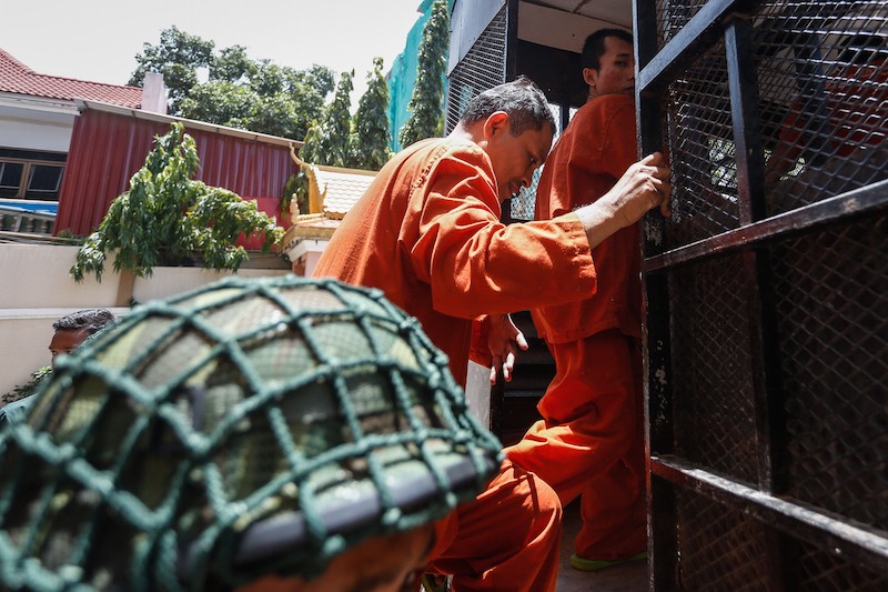 Suth Dina, the former ambassador to South Korea, climbs into a prison truck at the Phnom Penh Municipal Court on Monday. (Siv Channa/The Cambodia Daily)